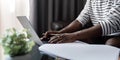 African American man working with laptop computer video calling and conference, remote work while sitting at sofa in Royalty Free Stock Photo