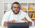 African-American man works at home office using computer, headset and other devices. Employee is having a conference Royalty Free Stock Photo