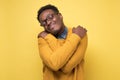 African american man in yellow clothes and glasses hugs himself Royalty Free Stock Photo