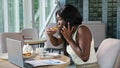 African-American manager talks on phone biting pizza in cafe