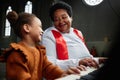 Woman teaching little girl to play piano in church Royalty Free Stock Photo