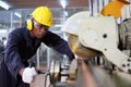 African American mechanic engineer worker wearing safety equipment is cutting copper tube using sawing machine in the factory