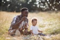 African dad blowing soap bubbles while playing with son Royalty Free Stock Photo