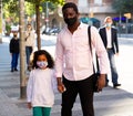African american man in protective mask walking with preteen daughter