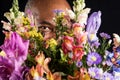 African American mischievously hides behind a colorful flower bouquet on black background. Mothers Day or Valentines Day concept.