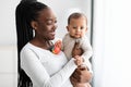 African American mom hugging her cute infant playing with toy Royalty Free Stock Photo