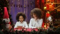 African American mom and little daughter reading a letter written for Santa Claus. Woman and girl sitting near Christmas Royalty Free Stock Photo