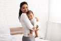 African American Mommy Carrying Little Baby Standing In Bedroom Indoor