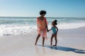 African american mother and daughter holding hands while looking at each other standing at beach Royalty Free Stock Photo