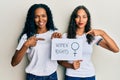 African american mother and daughter holding women rights banner smiling happy pointing with hand and finger