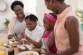 African american mother and grandmother teaching girl and boy cooking in the kitchen