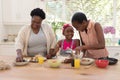 African american mother and grandmother teaching girl cooking in the kitchen