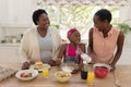 African american mother and grandmother teaching girl cooking in the kitchen