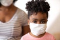 African American mother helping her daughter put on a face mask.