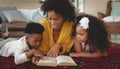 African American mother with her cute children lying on floor and reading a book Royalty Free Stock Photo