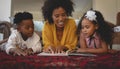 African American mother with her cute children lying on floor and reading a storybook