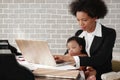 African american mother holding her baby boy on hands while working with laptop computer at home Royalty Free Stock Photo