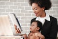 African american mother holding her baby boy on hands while working with laptop computer at home Royalty Free Stock Photo
