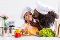 african american mother kissing her daughter in chef hat while cooking Royalty Free Stock Photo