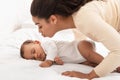 African American Mother Kissing Sleeping Baby Infant In Bedroom Indoors Royalty Free Stock Photo