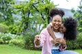 African American mother is playing piggyback riding with her young daughter while having a summer picnic in the public park for Royalty Free Stock Photo