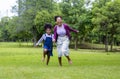 African American mother running barefoot on the grass lawn with her young daughter while having a summer picnic in the public park Royalty Free Stock Photo