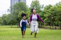 African American mother running barefoot on the grass lawn with her young daughter while having a summer picnic in the public park Royalty Free Stock Photo