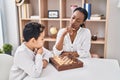 African american mother and son playing chess game sitting on table at home Royalty Free Stock Photo