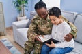 African american mother and son wearing soldier uniform reading book at home Royalty Free Stock Photo