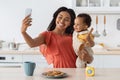 African American Mother Taking Selfie With Little Baby On Smartphone In Kitchen Royalty Free Stock Photo