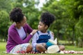 African American mother is teaching her young daughter to read while having a summer picnic in the public park for education and Royalty Free Stock Photo