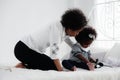 African american mother watching her girl child palying telephone in bedroom