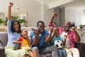 African american multi-generational family cheering while watching soccer match on tv at home