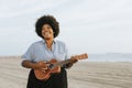 African American musician playing ukulele at the beach