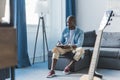 African american musician writing new song, his acoustic guitar standing