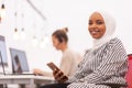 African american muslim girl with hijab working on a phone in modern office. Caucasian girl colleague with headset in the Royalty Free Stock Photo