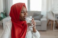 African american muslim woman drinking fresh mineral water from glass and looking aside at free space Royalty Free Stock Photo