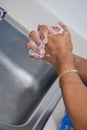 African-American nurse woman washing her hands in a stainless steel sink at a hospital or medical clinic Royalty Free Stock Photo