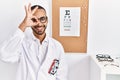 African american optician man standing by eyesight test doing ok gesture with hand smiling, eye looking through fingers with happy Royalty Free Stock Photo