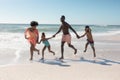 African american parents and children holding hands while running together at beach on sunny day Royalty Free Stock Photo