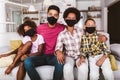 African American parents and cute small kids wearing protective masks at home.