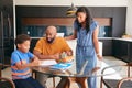 African American Parents Helping Son Studying Homework In Kitchen Royalty Free Stock Photo