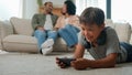 African American parents mother father talking on sofa little boy son child kid on floor play online video game on Royalty Free Stock Photo