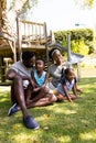 African american parents talking and playing with children while sitting on grassy field in park Royalty Free Stock Photo