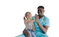 An African-American pediatrician holds a little happy girl patient on his lap, laughing and clapping his hands together Royalty Free Stock Photo