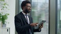 African American pensive thinking business man in office looking gazing out window using digital tablet computer device Royalty Free Stock Photo