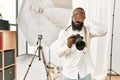 African american photographer man working at photography studio covering eyes with hand, looking serious and sad