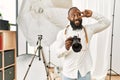 African american photographer man working at photography studio doing peace symbol with fingers over face, smiling cheerful Royalty Free Stock Photo