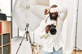 African american photographer man working at photography studio smiling cheerful playing peek a boo with hands showing face Royalty Free Stock Photo