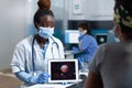 African american physician doctor holding tablet computer with covid19 ilustration